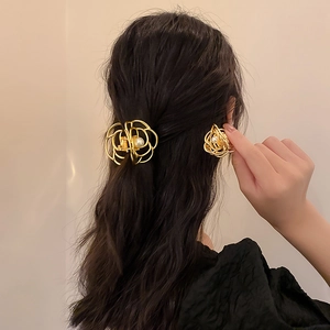 Detail of elegant gold metal rose hair claw clip with pearl center on a model