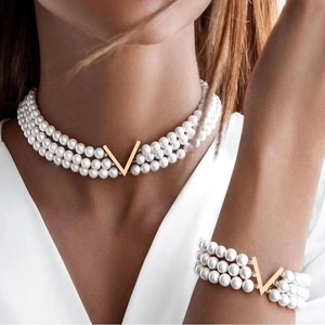 Parure bijoux en perles à trois rangs avec pendentif en V doré sur un mannequin femme