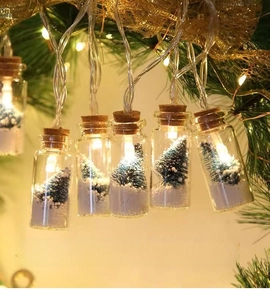 Close-up of glass wishing bottle lights with mini Christmas tree and warm LED glow