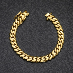Detail shot of golden Cuban link chain bracelet with butterfly box clasp on leather