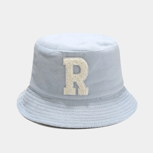 Detailed view of light blue bucket hat with plush letter R embroidery and textured fabric