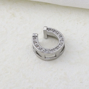 Macro shot of silver horse-shoe ear cuff set with fine clear zircon stones on paper