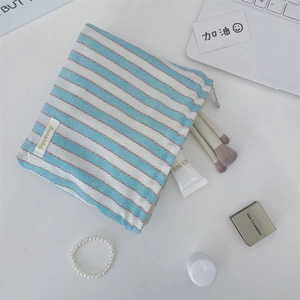 Close-up of striped canvas makeup bag with zipper closure and brand label