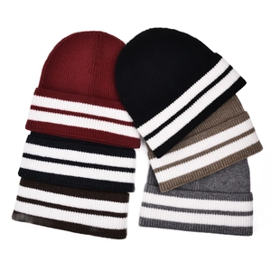 Close-up of five color variations of thick ribbed knit beanies with striped cuffs