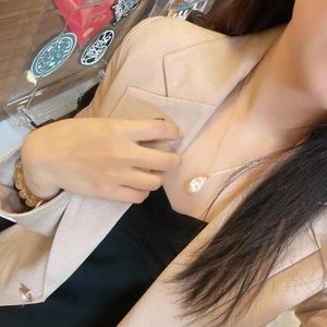 Baroque pearl pendant necklace with gold chain worn with an elegant apricot blazer suit
