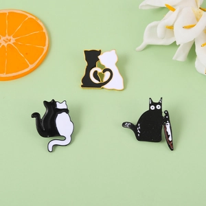 Detailed view of black and white cat enamel pins featuring a heart and cat with knife