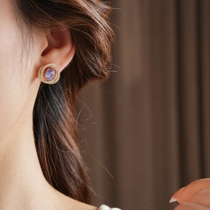 Dettaglio orecchino quadrato in oro con zircone viola e diamanti sul lobo