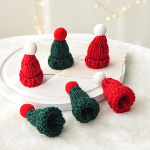 Close-up of mini knitted Christmas hats in red and green colors with pom poms