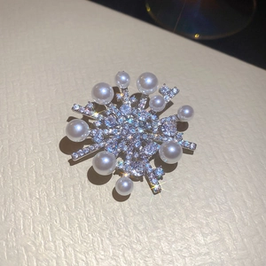 Detail of snowflake brooch featuring shimmering zircons and elegant white pearls