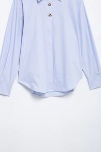 Detailed flat lay of light blue striped button-down shirt with curved hem and cuffs