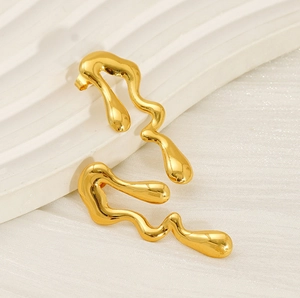 Macro shot of liquid irregular golden earrings with a polished molten metal wave texture