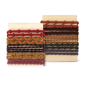 Detalle de gomas de pelo trenzadas y anudadas de colores en tarjetas de madera