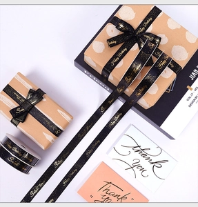 Close-up of black satin ribbon with gold foil Happy Birthday text for gift wrapping