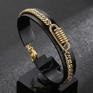 Dettaglio ravvicinato di un bracciale a maglia cubana in acciaio dorato con molla a spirale