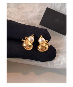 Gros plan sur des boucles d'oreilles gourde dorées avec perles blanches et cristaux