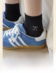 Close-up of black ribbed cotton socks featuring a delicate white embroidered bow design
