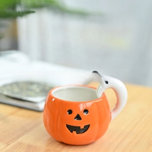 Close-up of a pumpkin-shaped ceramic mug with a white ghost handle for Halloween