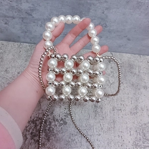 Close-up of handmade mini pearl and silver metal bead crossbody bag with chain strap