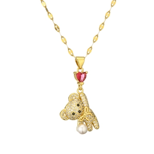 Golden bear pendant necklace with red heart gemstone and pearl detail on fine chain