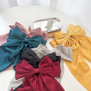 Flat lay of large satin bow hair clips in pink, green, burgundy, and silver tones