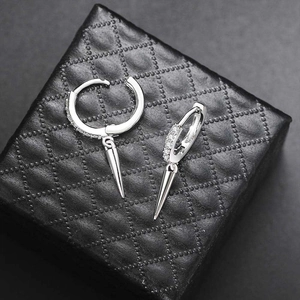 Detailed view of silver hoop earrings with zircon stones and punk spike charms on jewelry box