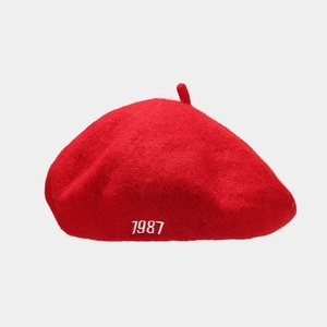 Detail of red wool beret with white 1987 embroidery and soft felt texture