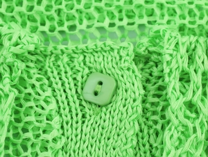 Close-up of vibrant green knit cardigan featuring mesh texture and a matching square button
