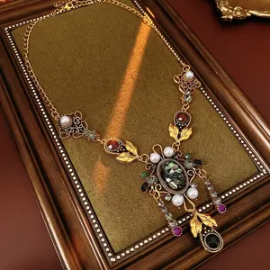 Collier vintage doré avec pierre noire ovale, perles et gemmes colorées sur tissu vert