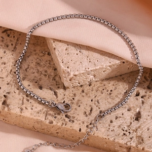 Detail view of silver stainless steel box chain anklet with lobster clasp on stone