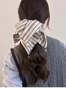 Détail d'un chouchou à rayures avec perles sur la queue de cheval d'un mannequin
