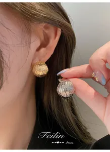 Detail of dome earrings featuring textured vertical metal grooves in gold and silver finish