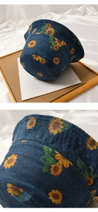 Detail of dark blue denim bucket hat featuring bright sunflower print and fabric texture