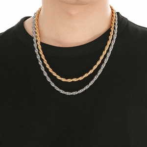 Gros plan de colliers torsadés en argent et or en acier inoxydable sur un t-shirt noir