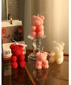 Detailed view of four handmade rose bear candles in red, white and pink colors