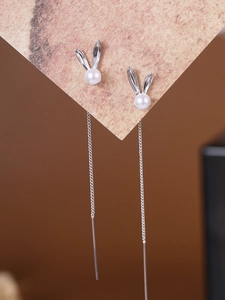 Detailed close-up of silver long tassel earrings with cute bunny shape and white pearl