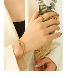 Close-up of gold plated knot bracelet and chunky curb ring on model with minimalist style