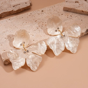 Retro butterfly resin earrings with diamonds on elegant beige stone display