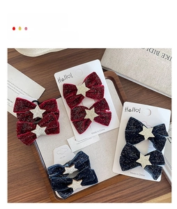 Detail of velvet bow hair clips with gold stars in red and navy on display card