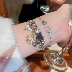 Detail of layered pink butterfly and heart charm bracelets worn on woman wrist