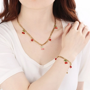 Detail of 18K gold plated stainless steel necklace and bracelet with red cherry pendants