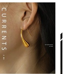 Close-up of a elegant golden teardrop earring with high-polish finish on a model