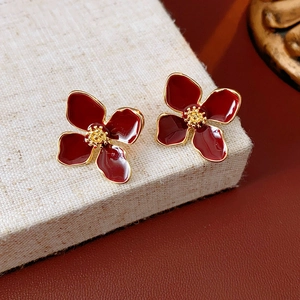 Close-up of red French flower stud earrings with golden edges on linen texture base