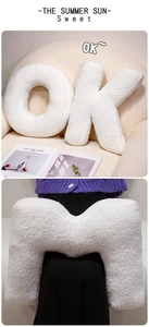 Detail of white boucle letter pillows in O, K, and M shapes for modern sofa decor