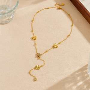 Élégant collier en Y papillon plaqué or avec pendentif goutte de cristal sur fond texturé