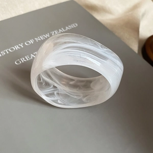 Detail of translucent white marble resin bangle resting on a grey hardcover book