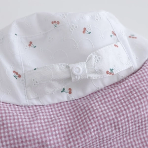 Close-up of children's sun hat with cherry print, daisy embroidery and bow detail