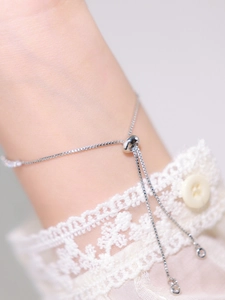 Detail of silver box chain bracelet featuring an adjustable slider clasp and round charms