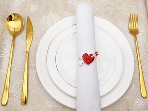 Detail of a red heart and arrow napkin ring with gold finish and rhinestones