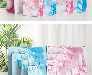 Detail of pink and blue marble gift bags with gold Happy Times lettering and ribbon handles
