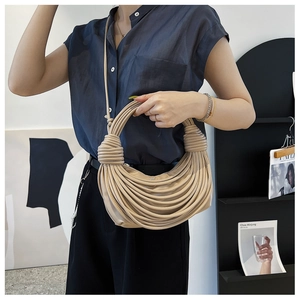 Dettaglio della borsa a mano intrecciata beige con texture in pelle PU e design a pieghe